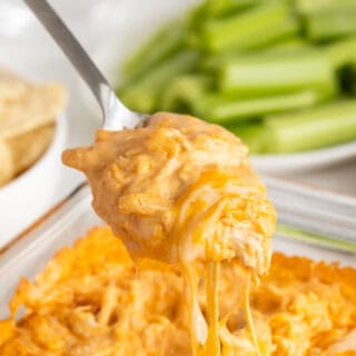 A scoop of buffalo chicken dip being lifted from a baking dish