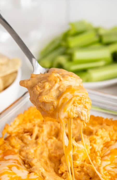 A scoop of buffalo chicken dip being lifted from a baking dish