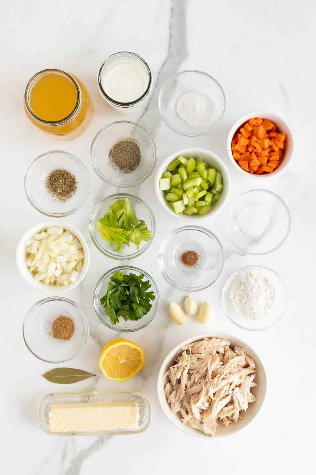 Overhead shot of ingredients for making chicken and rolled dumplings on a white marble surface before cooking