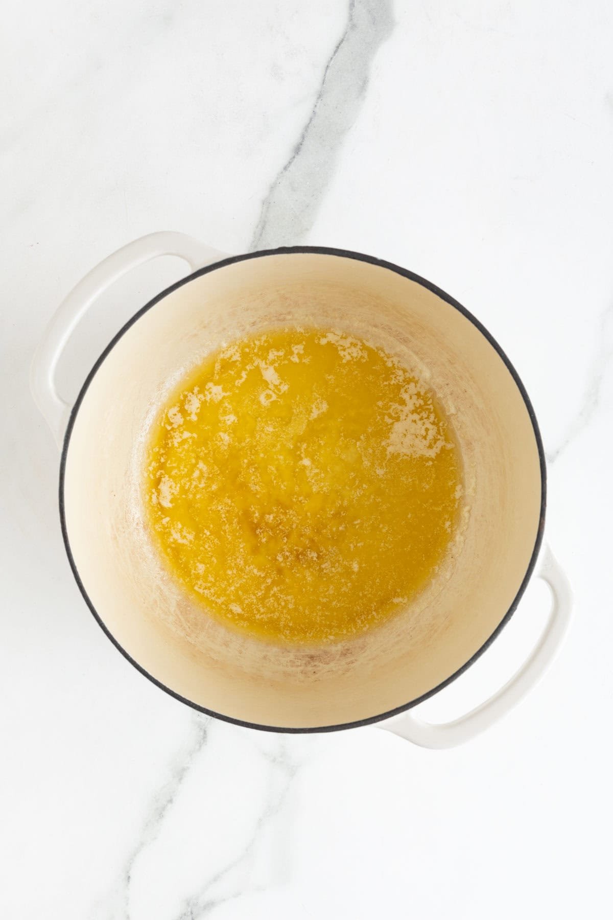 Closeup of melted butter in a white Dutch oven pot