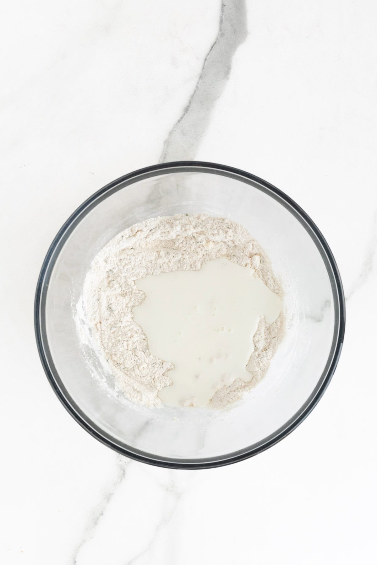 Buttermilk being added to the dough mixture in a bowl