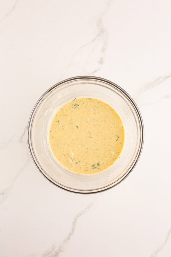 Liquid base for crab cakes mixed together in glass bowl