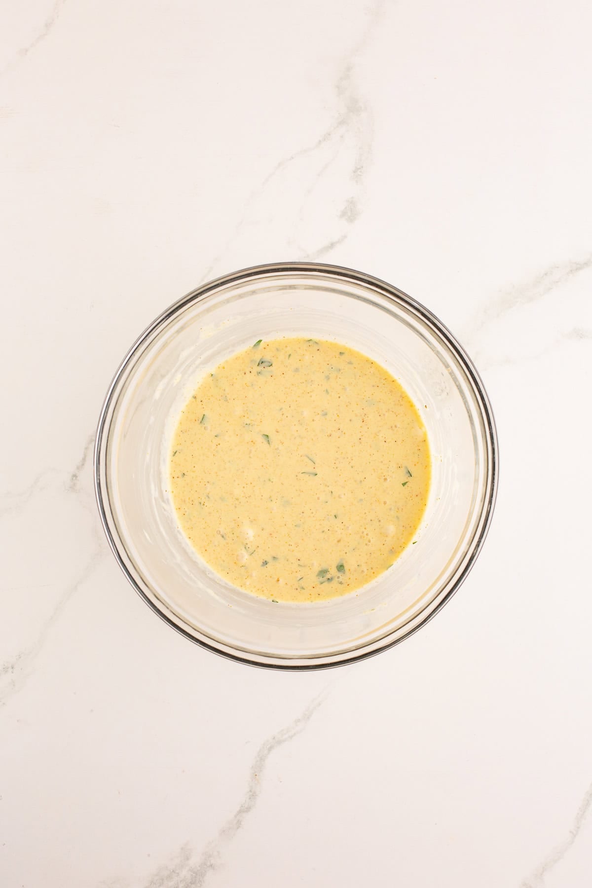 Liquid base for crab cakes mixed together in glass bowl