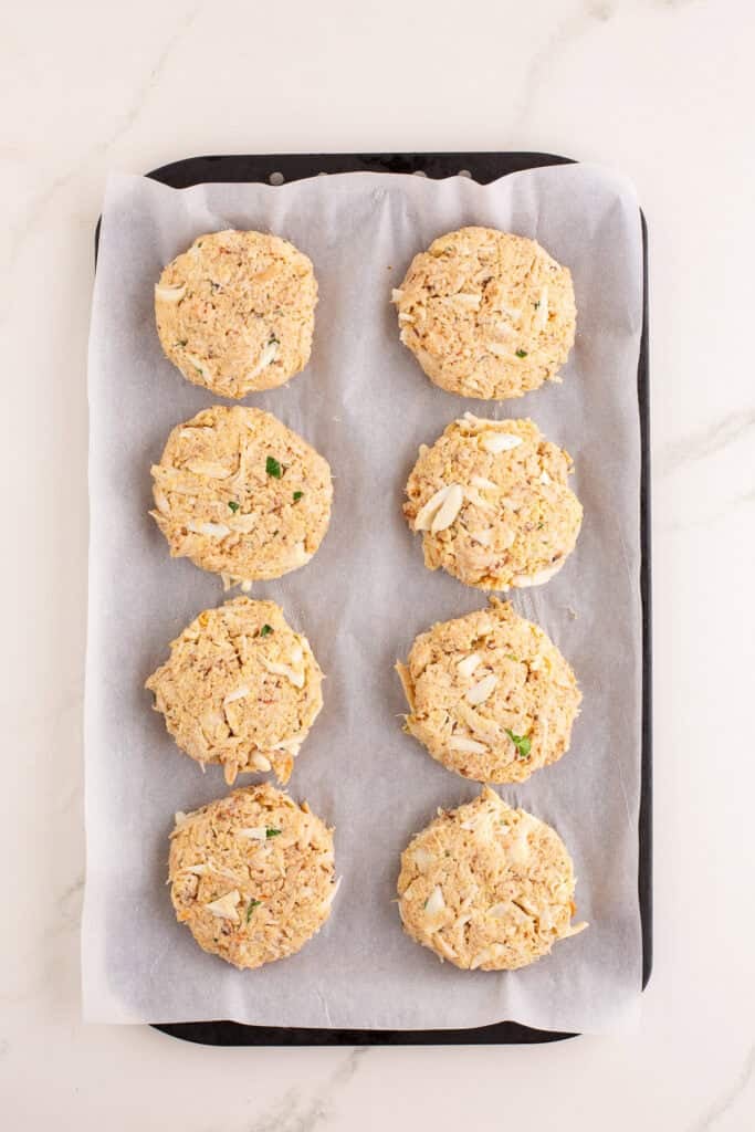 Shaped crab cakes on a parchment lined sheet pan