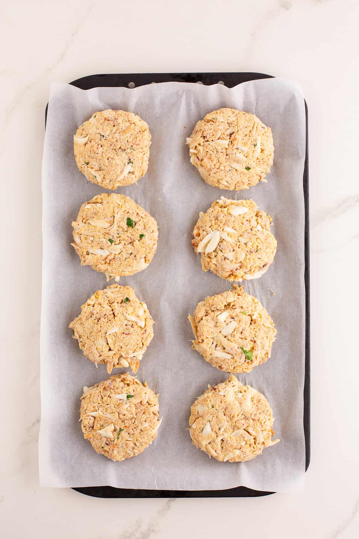 Shaped crab cakes on a parchment lined sheet pan