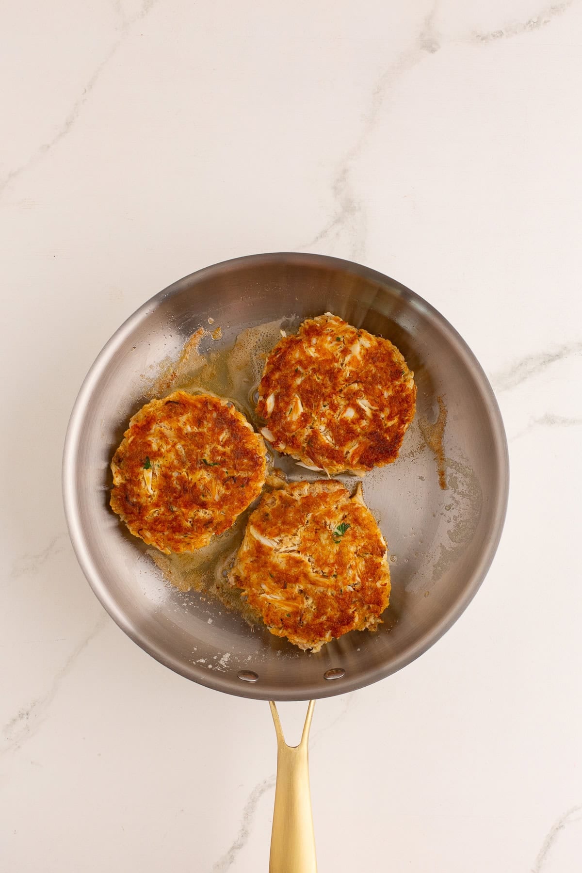 Crab cakes in a skillet frying