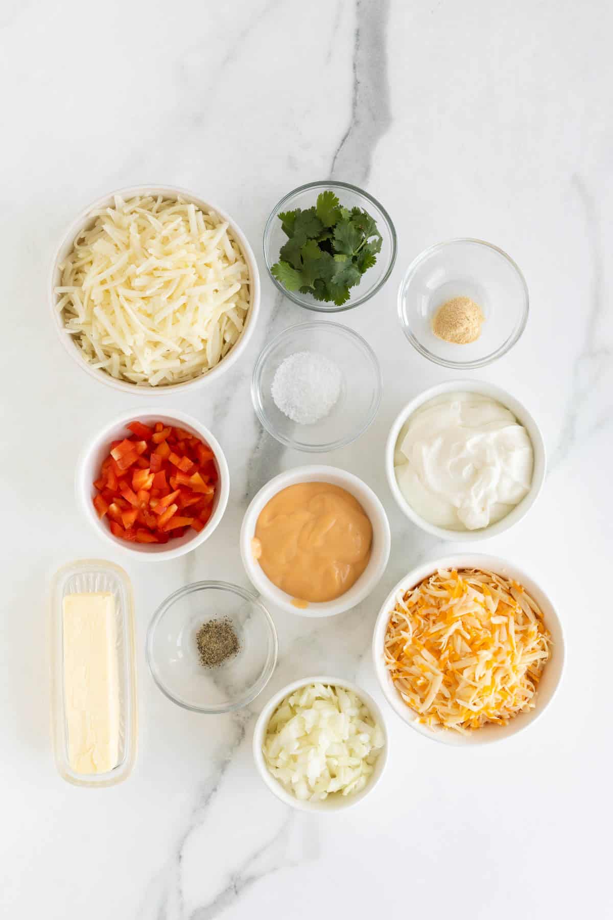 Overhead shot of ingredients for making hashbrown casserole on a marble surface before cooking