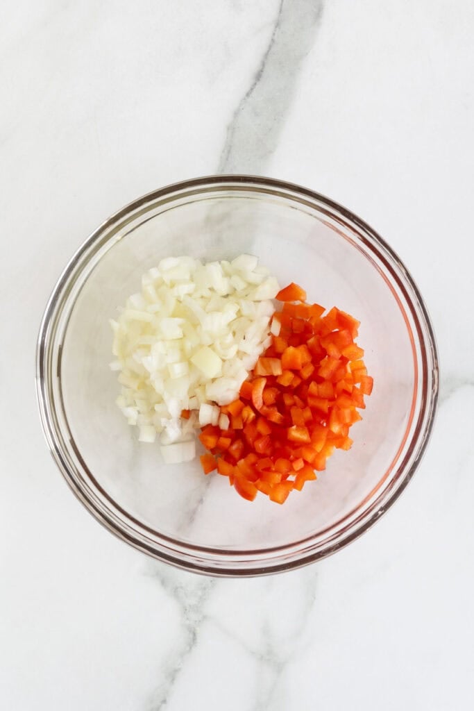 Glass bowl with diced onions and red bell peppers