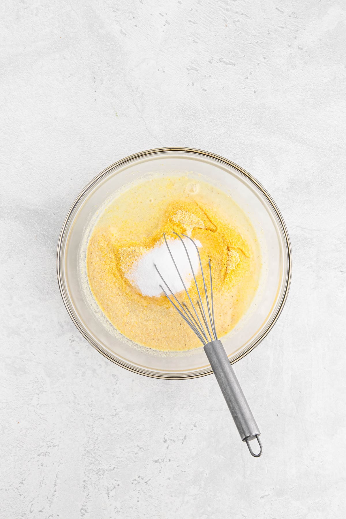 cornmeal, sugar, salt and boiling water added to a glass bowl being whisked