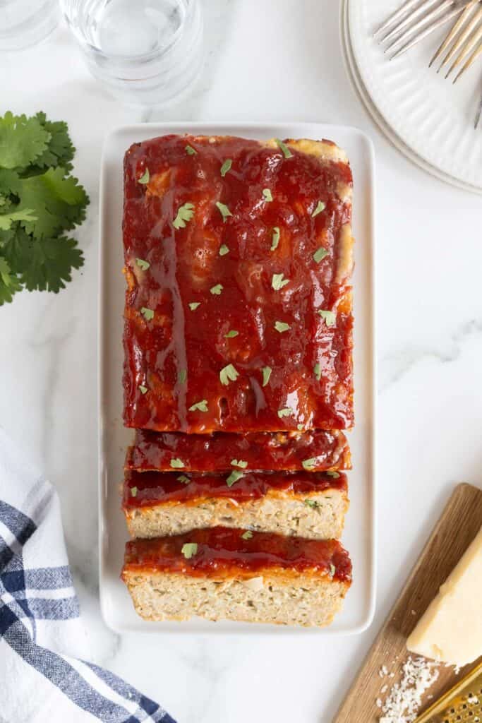 Overhead view of the fully cooked turkey meatloaf sliced on a serving platter, garnished with chopped parsley