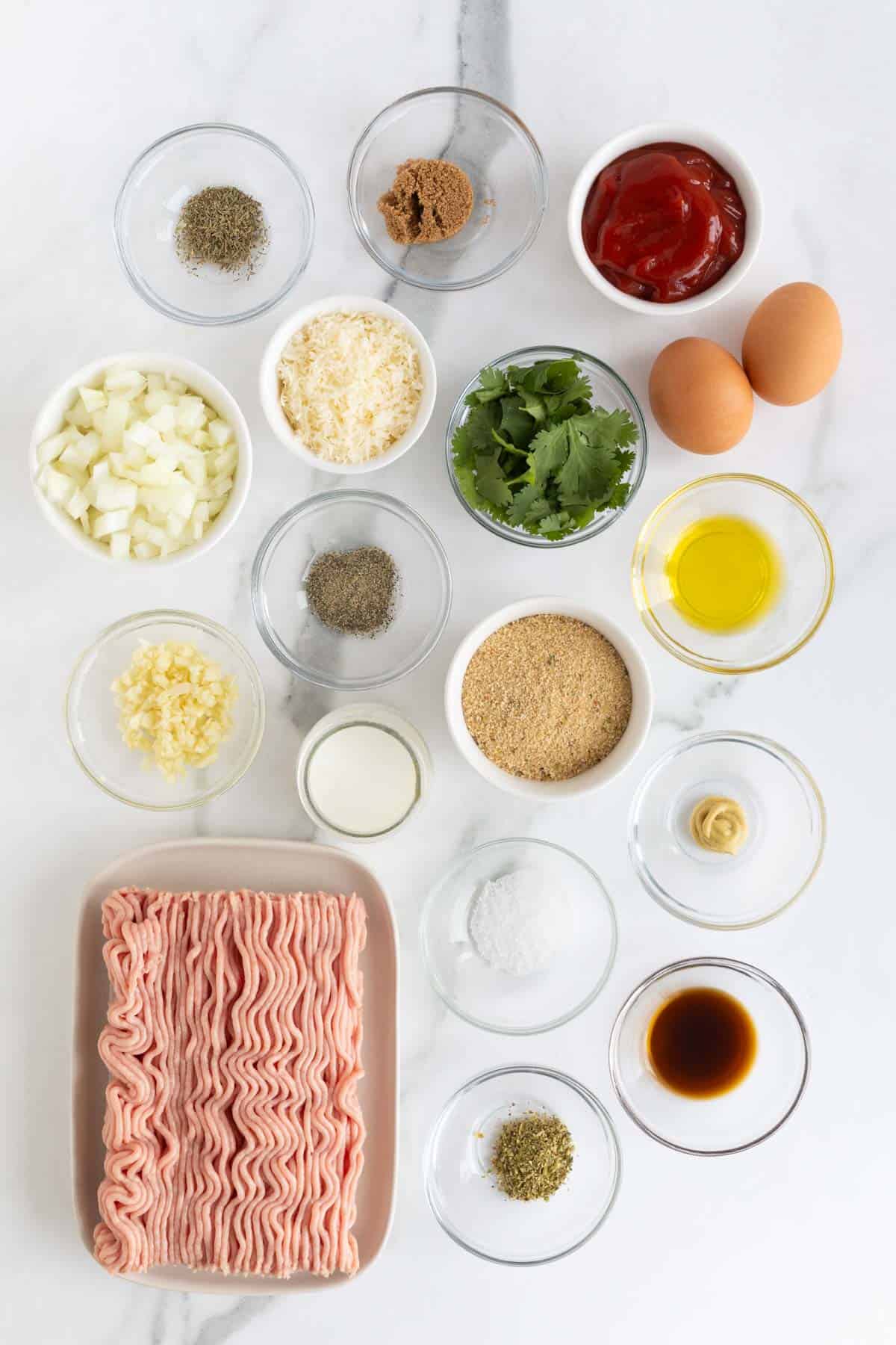 Overhead shot of ingredients for making turkey meatloaf on a marble surface before cooking