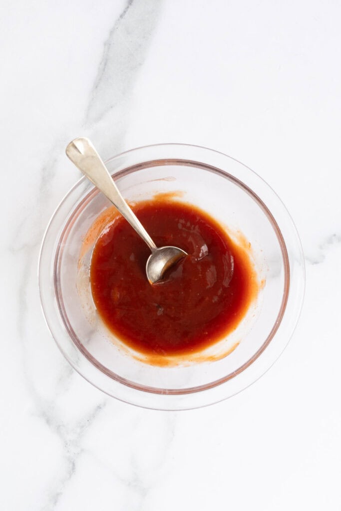 The ketchup glaze fully mixed with a spoon resting in the bowl