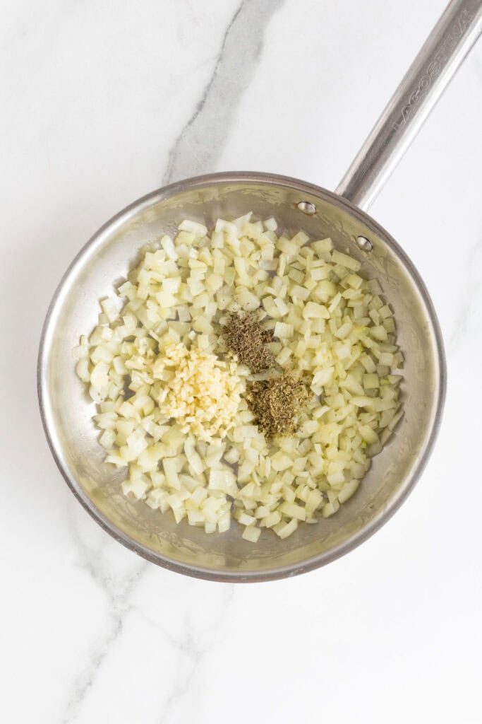 Garlic and dried herbs added to the sautéed onions in the skillet