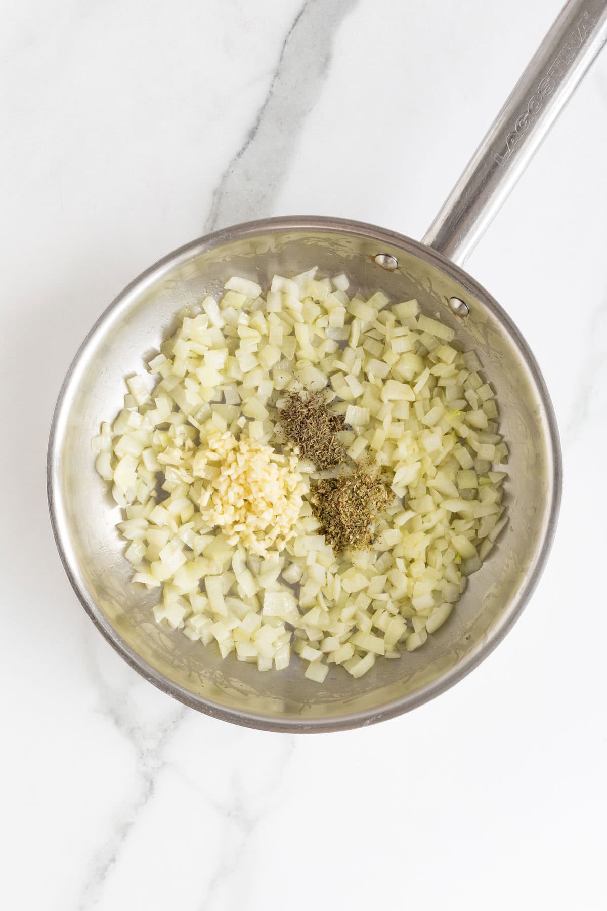Garlic and dried herbs added to the sautéed onions in the skillet