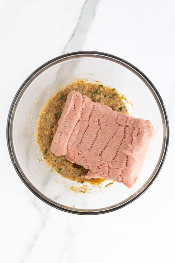 Raw ground turkey added on top of the breadcrumb and herb mixture