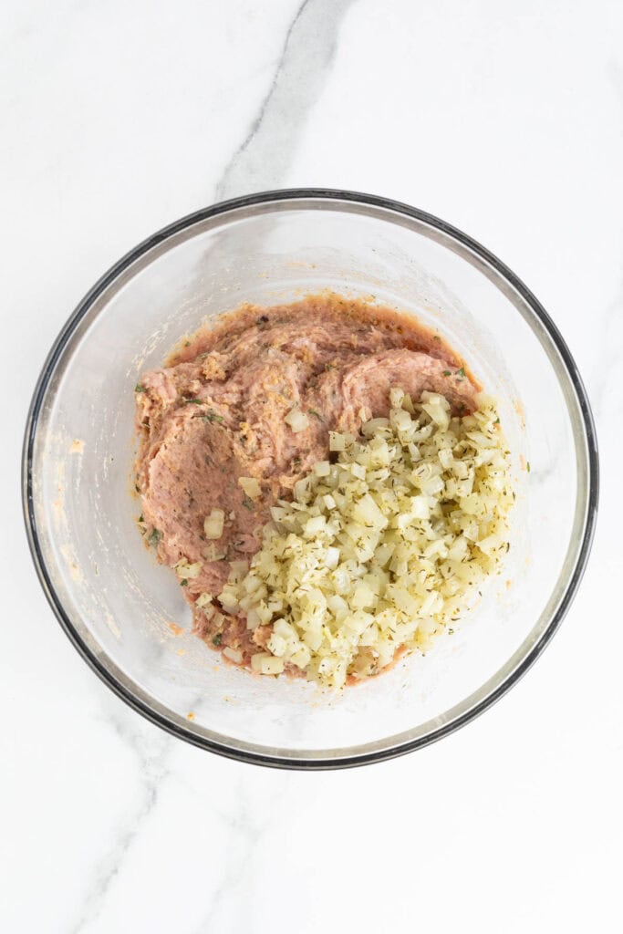 Cooked onion and herb mixture added to the turkey blend in the bowl