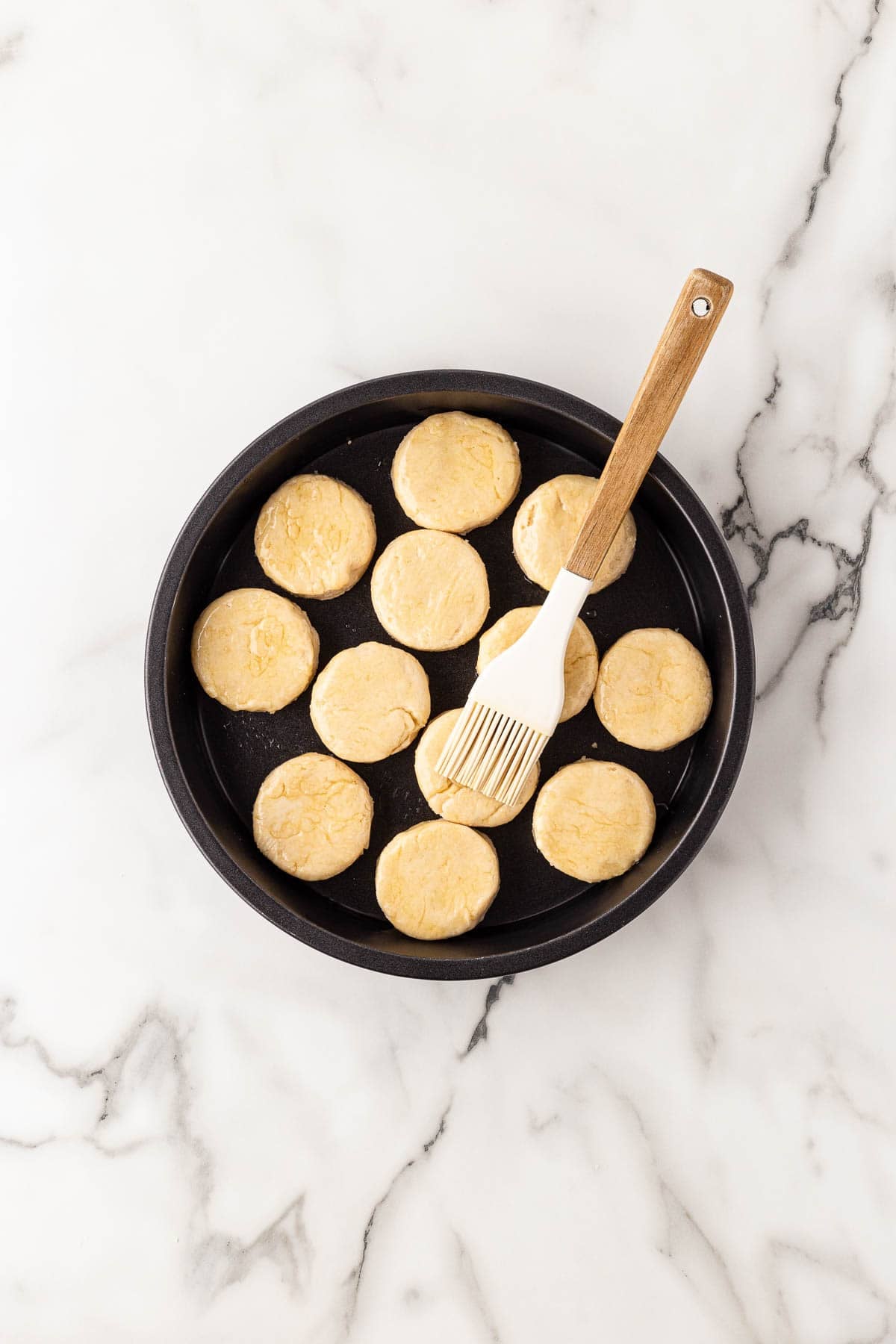 Unbaked biscuits in pan brushed with butter
