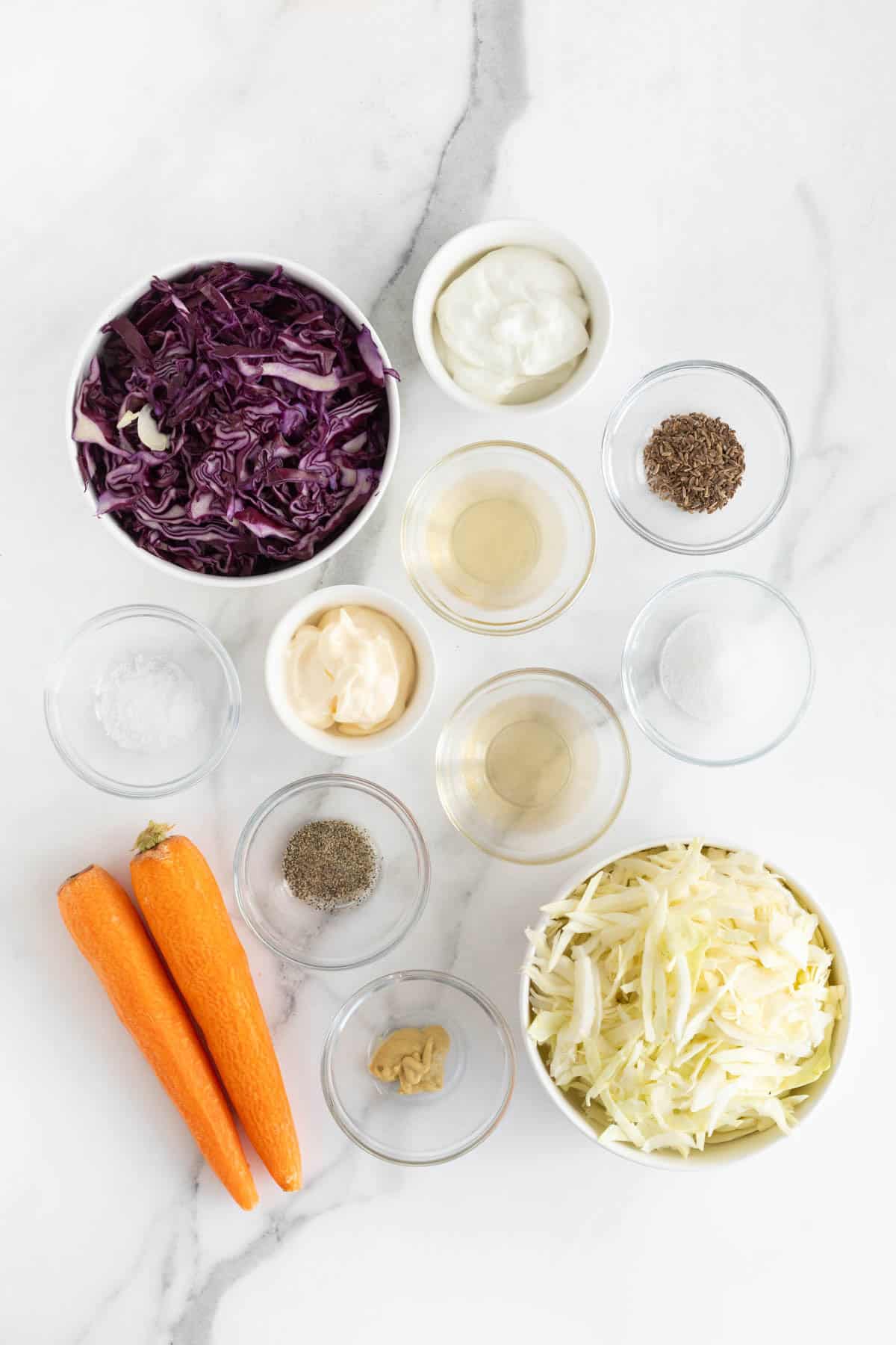 Overhead shot of ingredients for making classic coleslaw on a marble surface before mixing