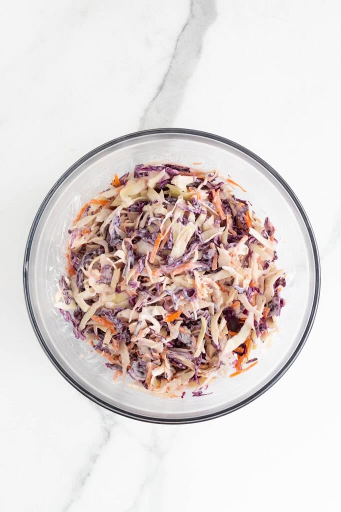 Tossed classic coleslaw in a glass bowl on countertop