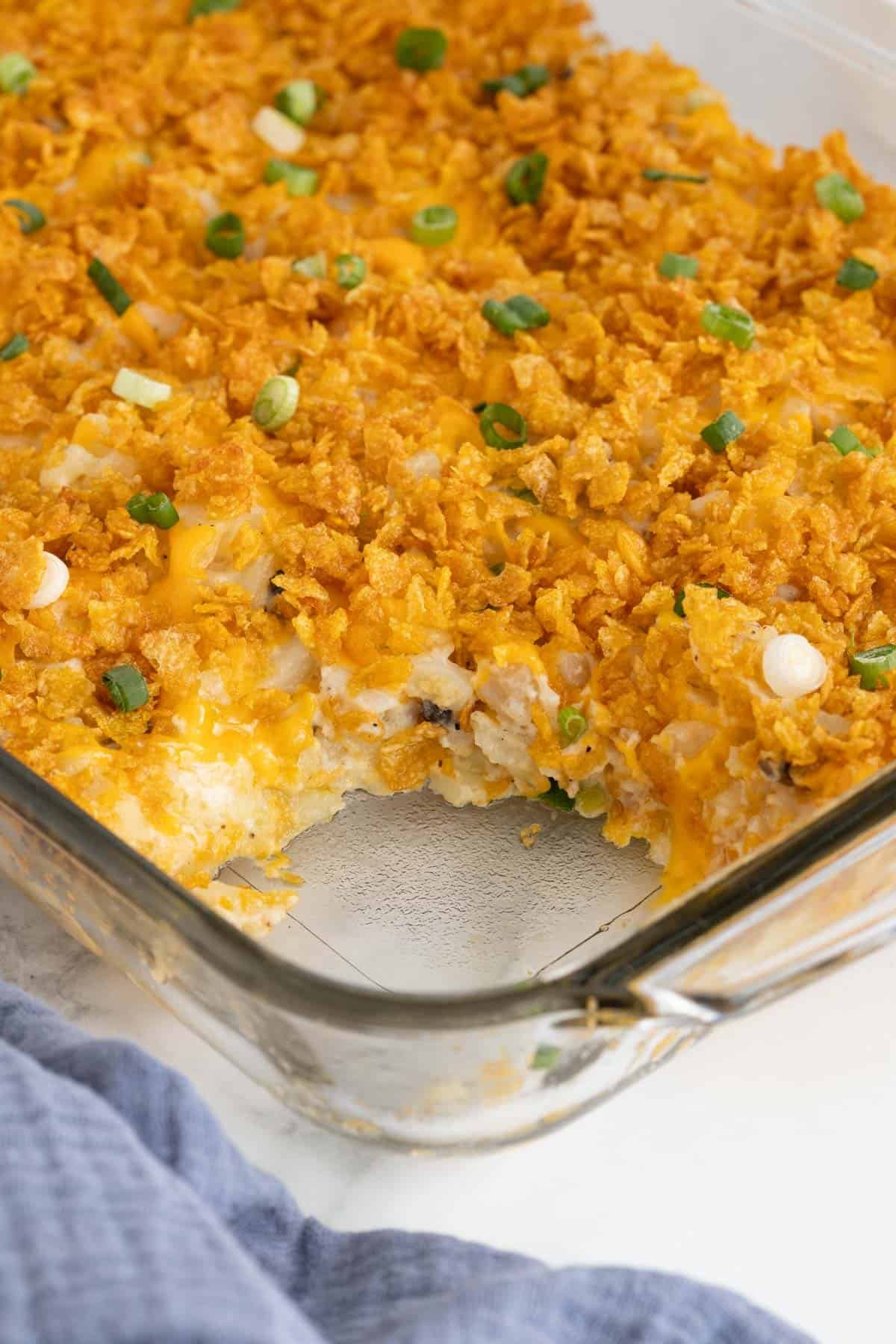 Closeup of partially scooped funeral potatoes in a glass baking dish