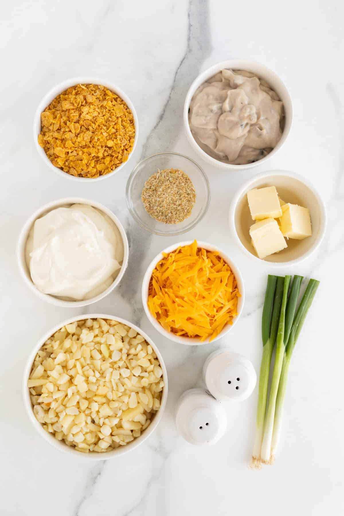 Overhead shot of ingredients for making funeral potatoes on a marble surface before cooking