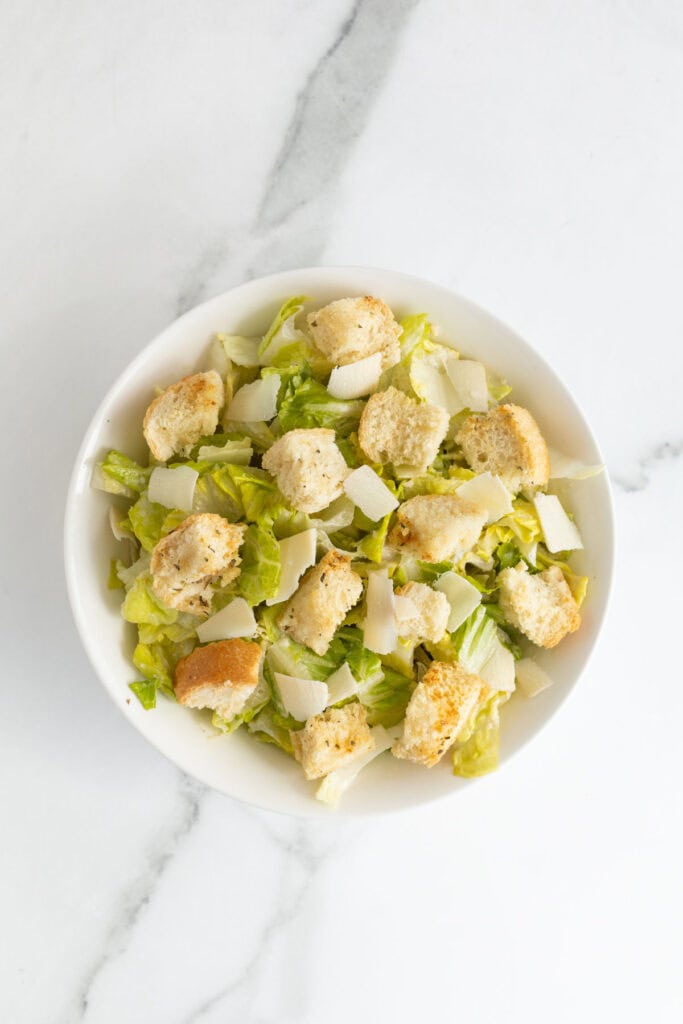 Completed caesar salad recipe in a white bowl on countertop