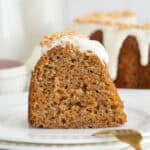 A slice of a carrot bundt cake on a white plate with a gold fork