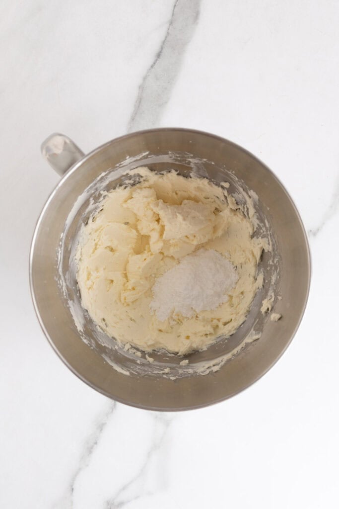 Metal mixing bowl filled with whipped cream cheese and powdered sugar