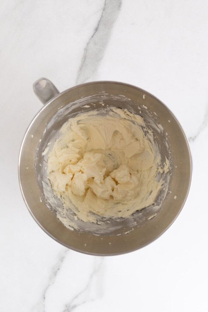 Creamy frosting fully whipped in a metal mixing bowl, smooth and fluffy in texture