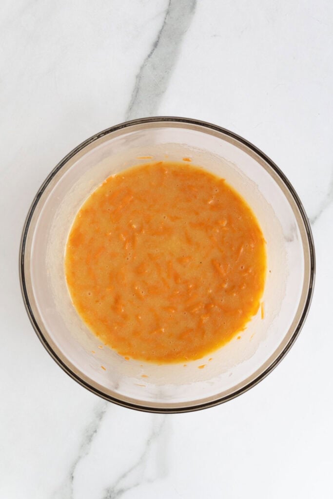 Wet carrot cake mixture stirred until fully combined in a glass mixing bowl