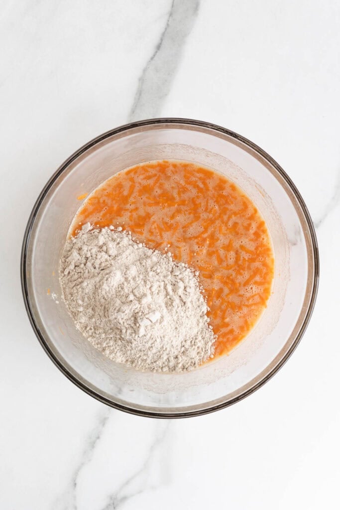 Wet and dry ingredients partially combined in a large glass bowl