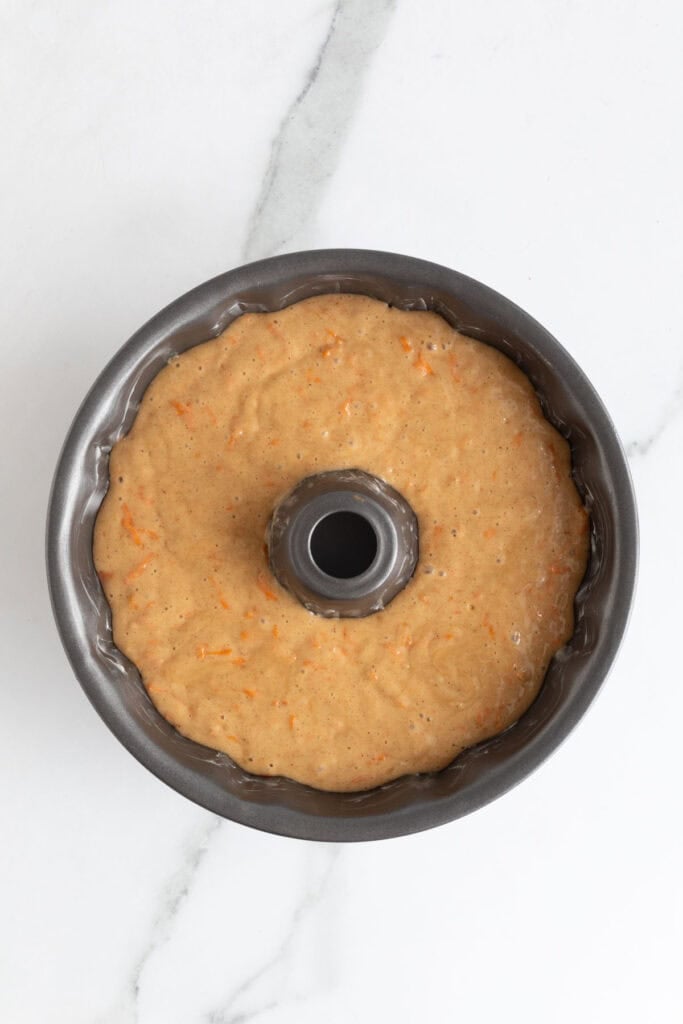 Carrot cake batter poured evenly into a greased Bundt pan