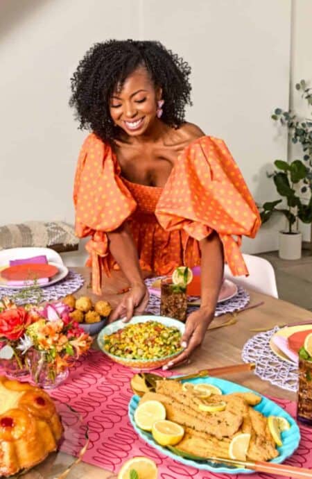 Jocelyn in orange smiling and serving at table