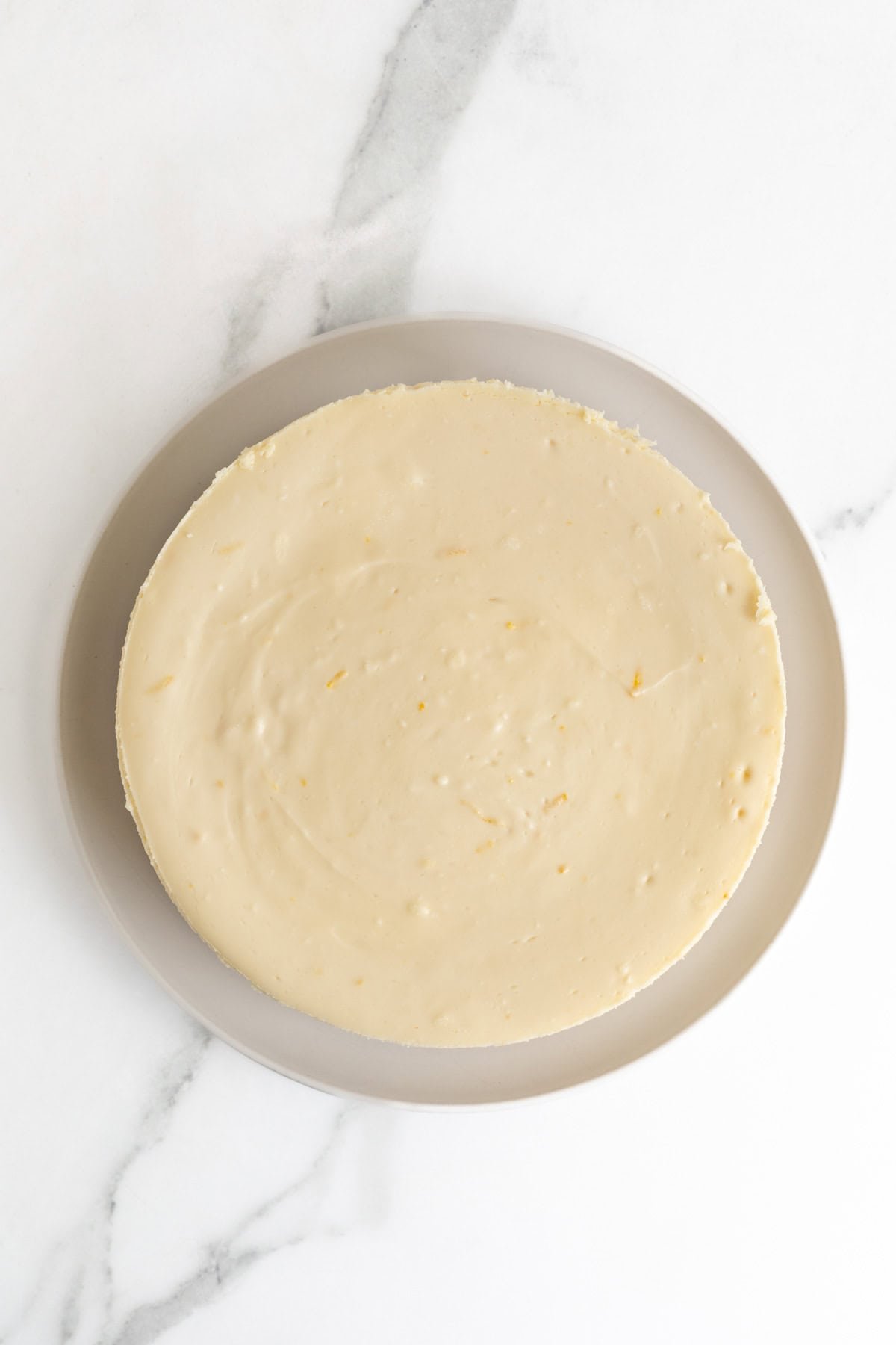Baked and cooled cheesecake layer removed from springform pan and placed on a plate