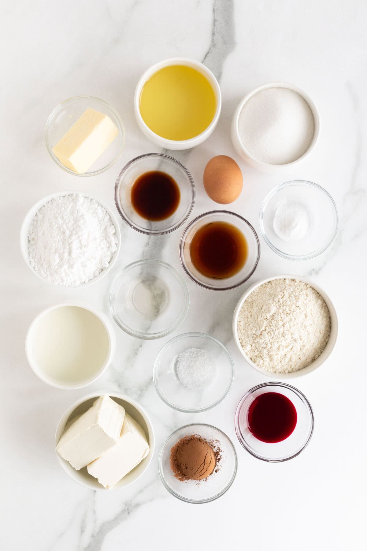 Overhead shot of ingredients for making red velvet cupcakes on a marble surface before mixing