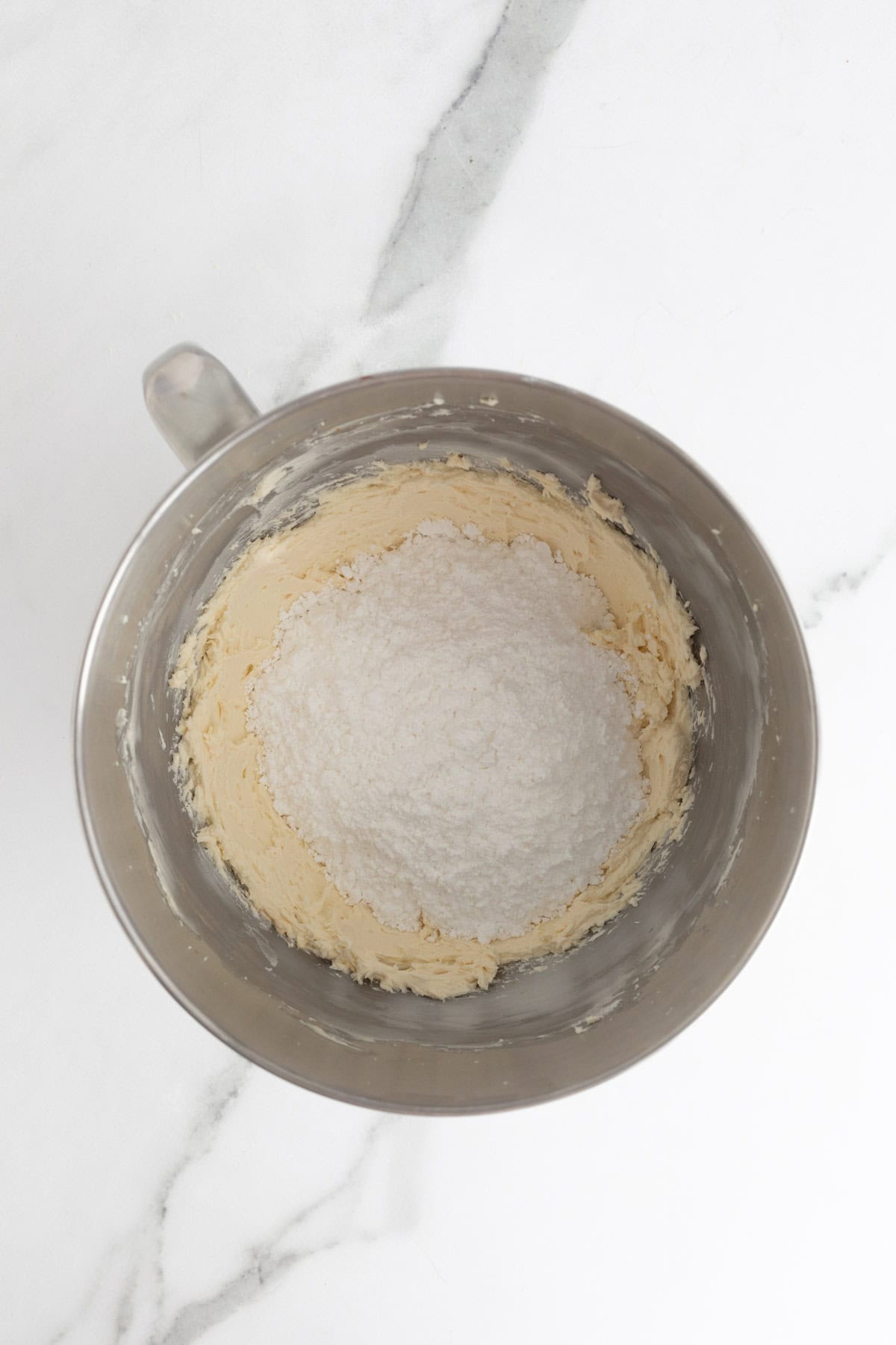 Powdered sugar added to the butter and cream cheese mixture in the bowl