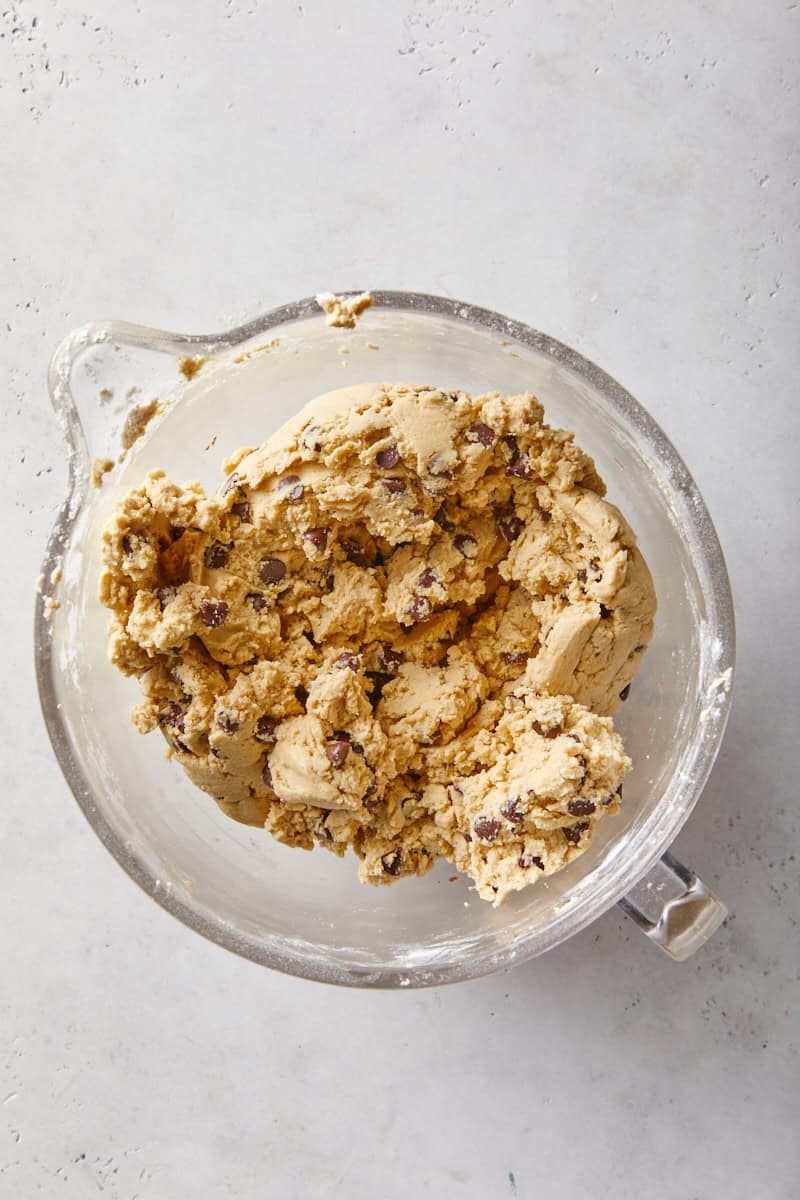 Chocolate chip cookie dough mixed with chocolate chips in a stand mixer bowl