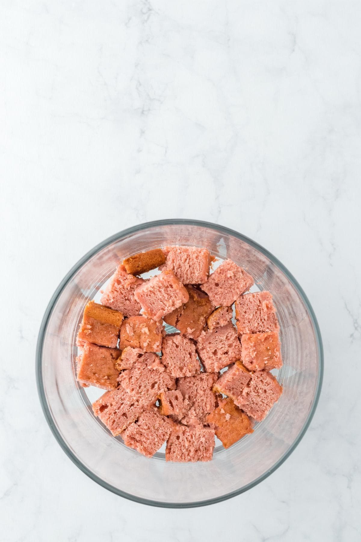 Cubed strawberry cake pieces in a glass bowl for trifle layering