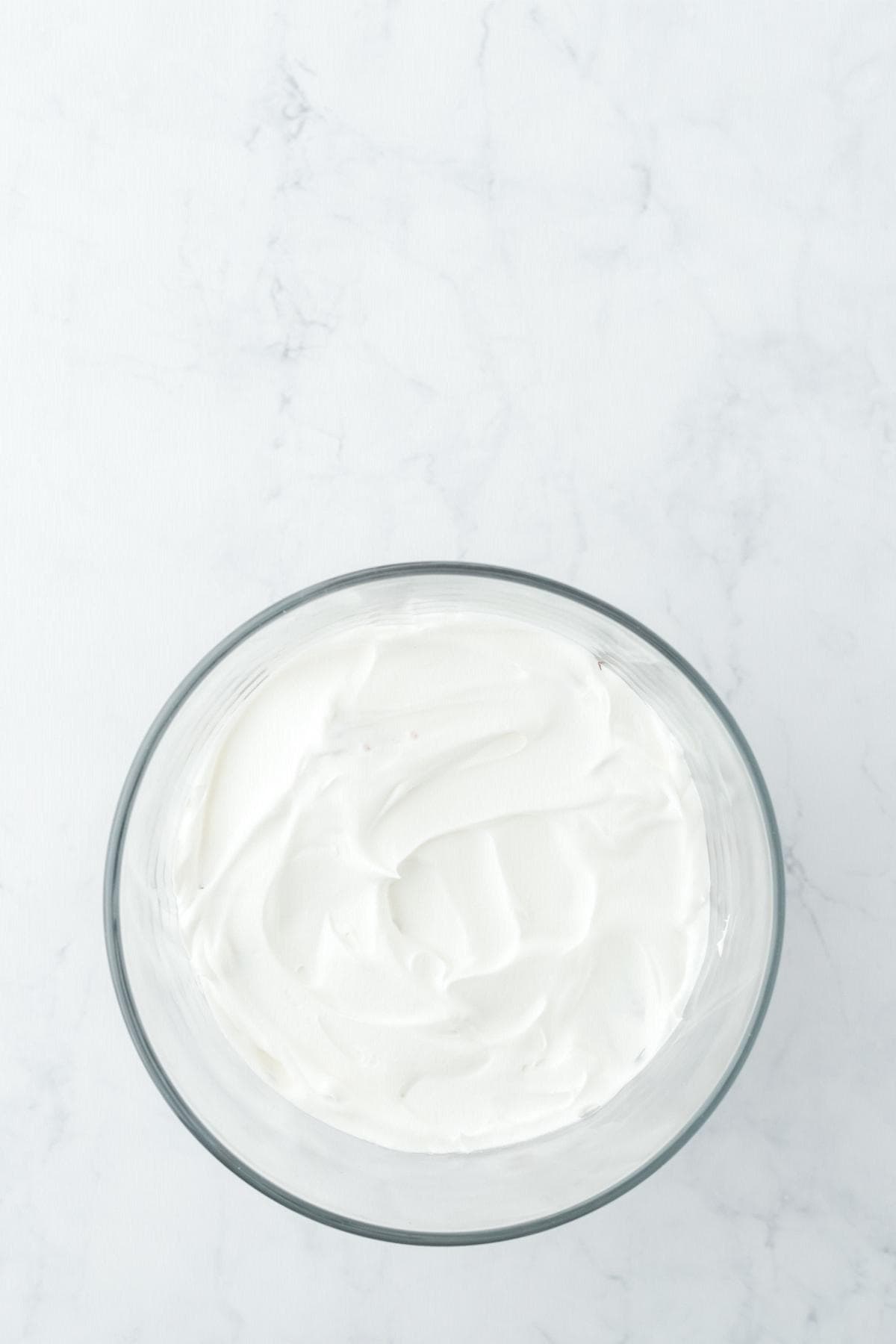 Smooth whipped cream in a glass bowl, ready for layering