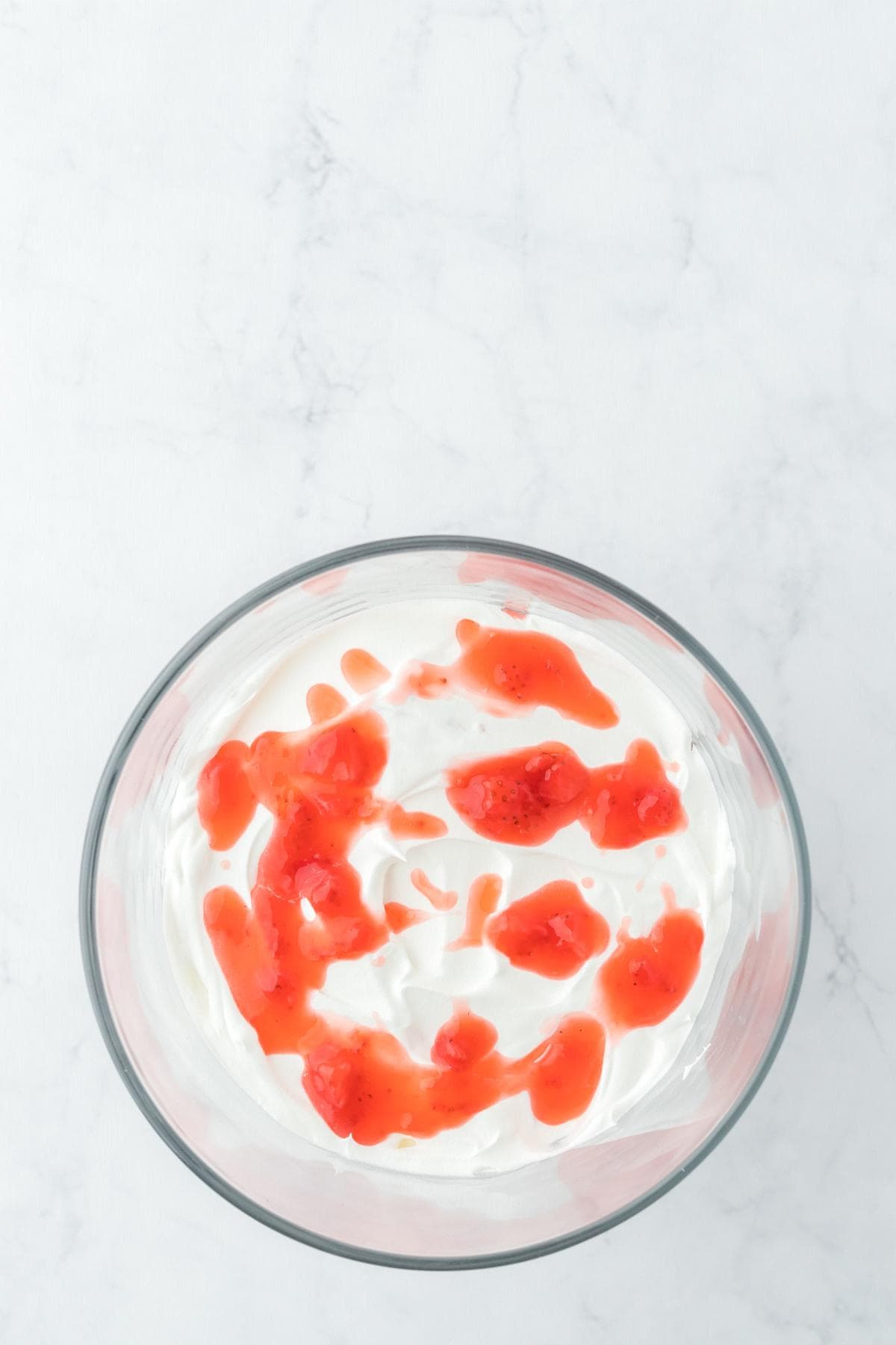 Whipped cream topped with spoonfuls of strawberry sauce