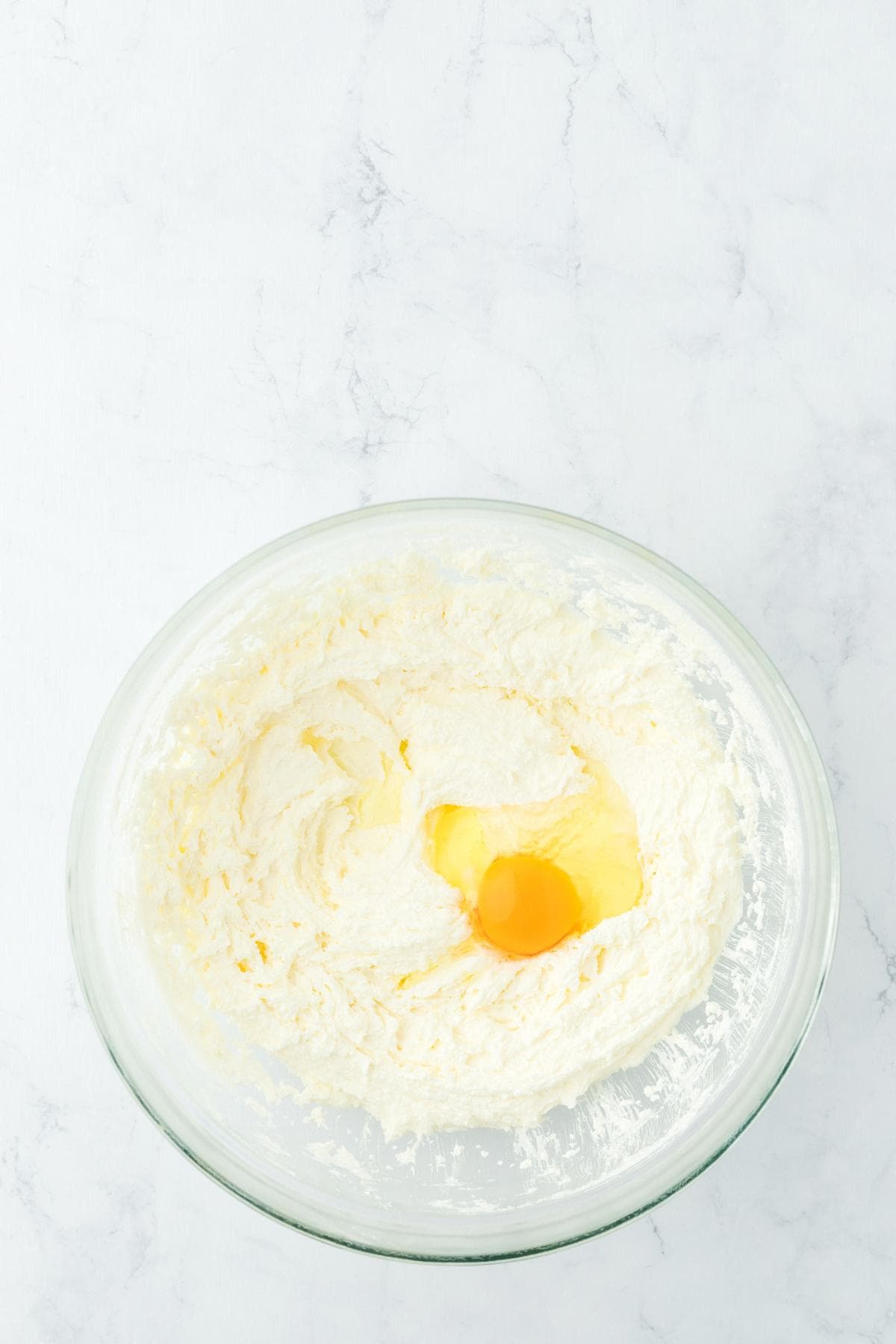 Creamed butter mixture with an egg added in a mixing bowl
