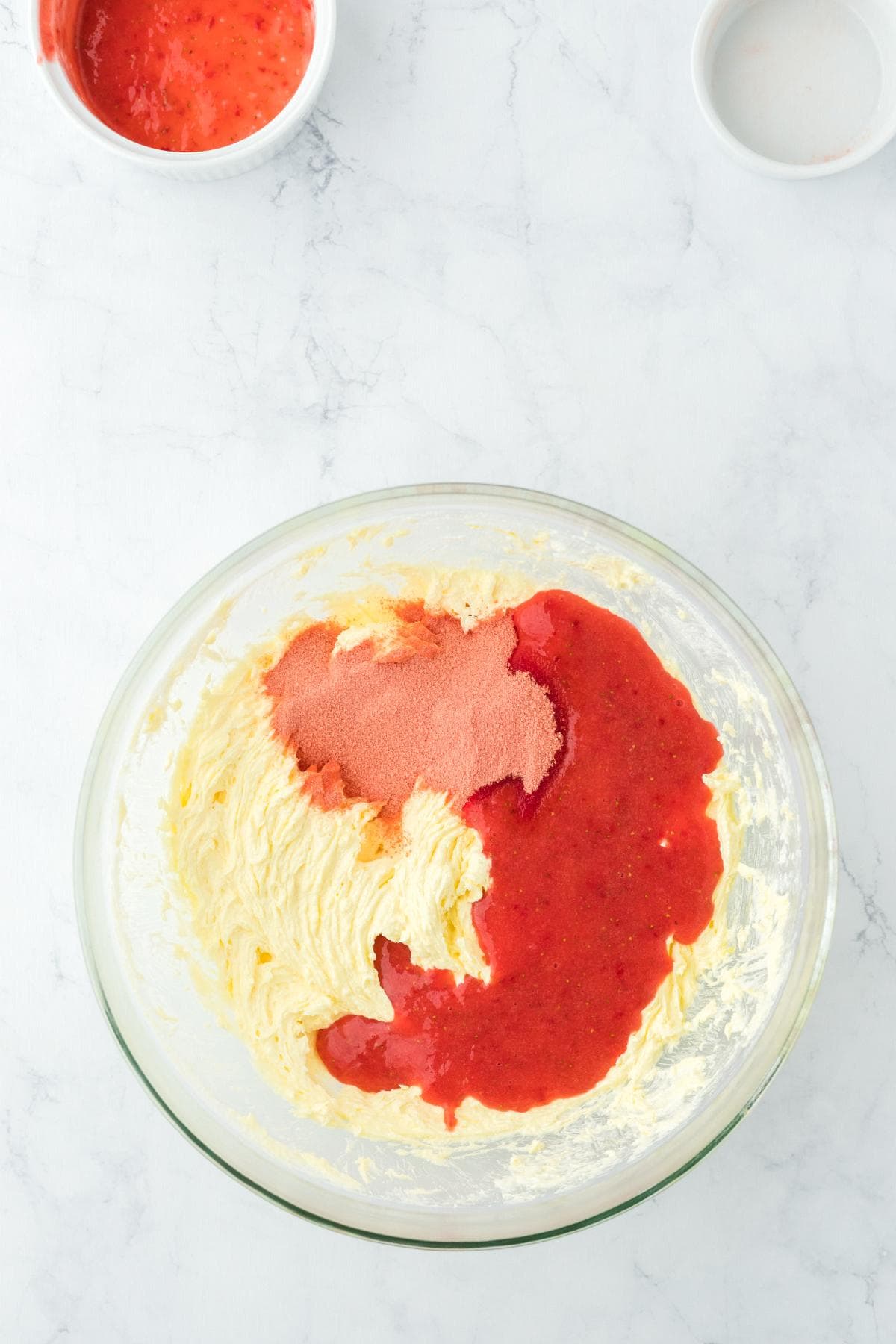 Strawberry puree and gelatin added to creamed mixture in a bowl