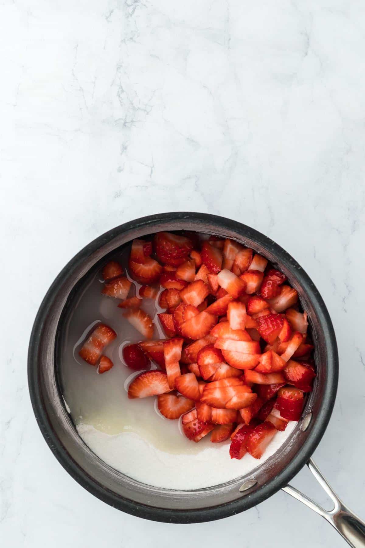 Fresh chopped strawberries added to sugar, water, and cornstarch in a saucepan before cooking