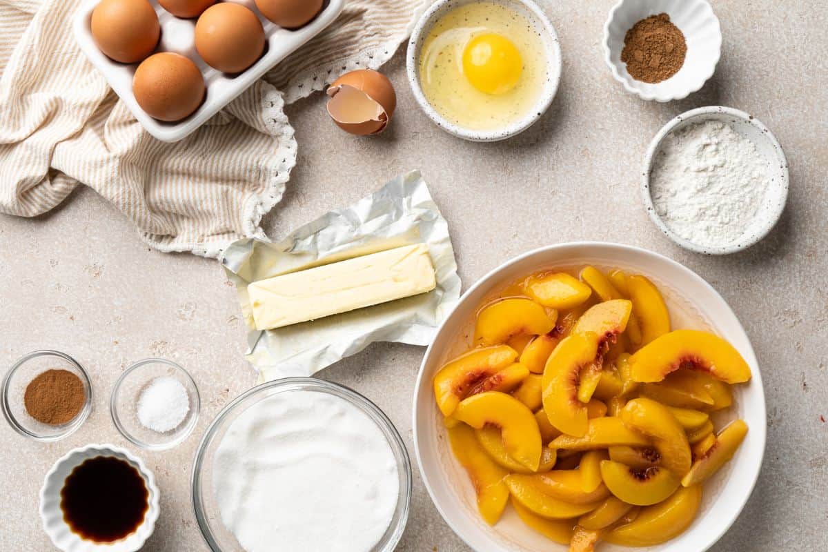 Overhead shot of Southern peach cobbler ingredients on a beige countertop