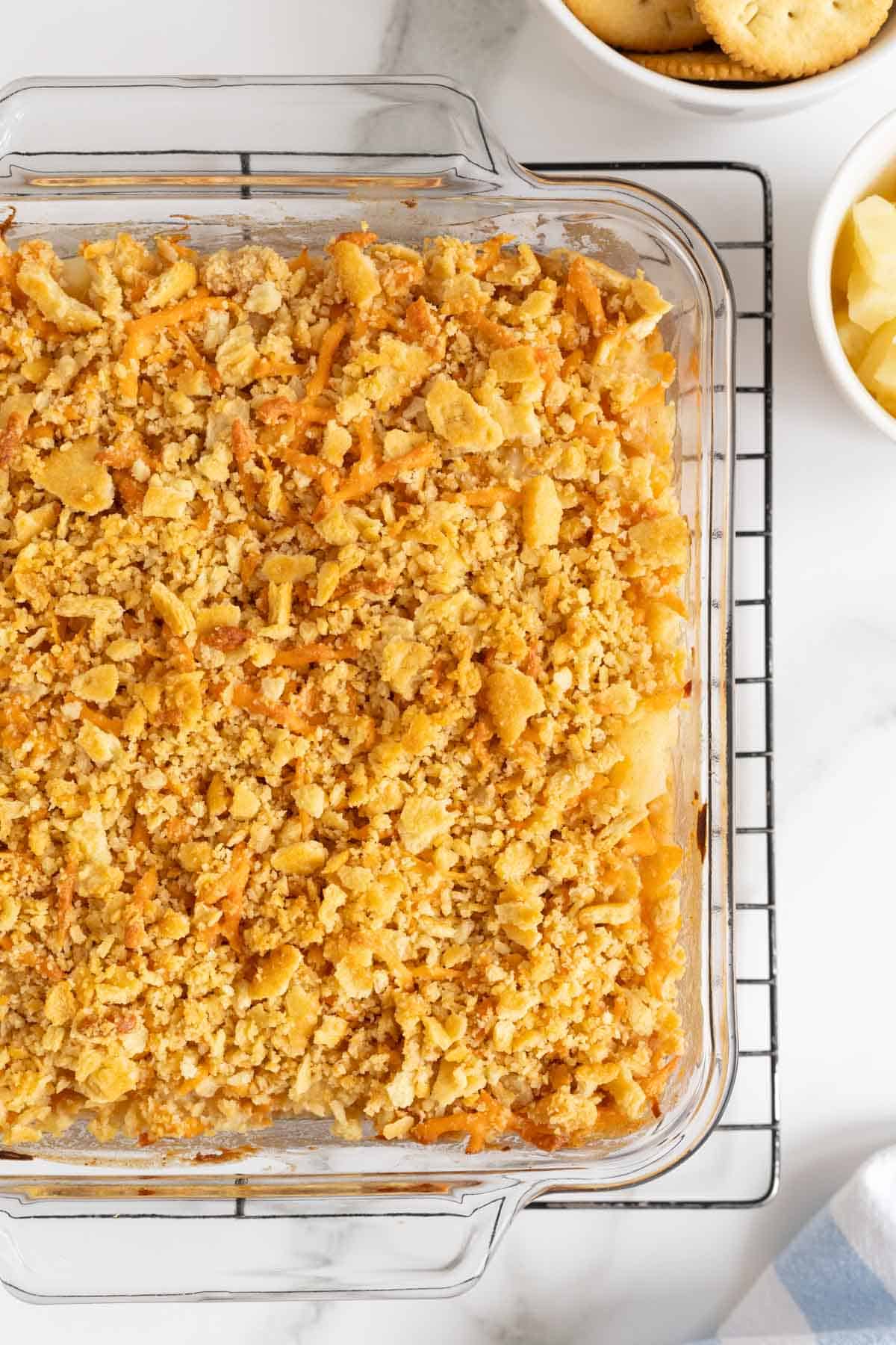 Overhead shot of a pineapple casserole with golden cracker topping, cooling in a cooling rack