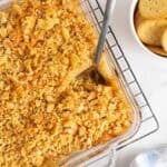 Overhead shot of a pineapple casserole with a spoon in it, sitting on a cooling rack