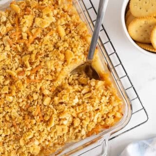 Overhead shot of a pineapple casserole with a spoon in it, sitting on a cooling rack