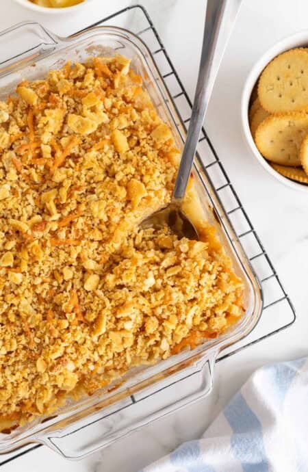 Overhead shot of a pineapple casserole with a spoon in it, sitting on a cooling rack