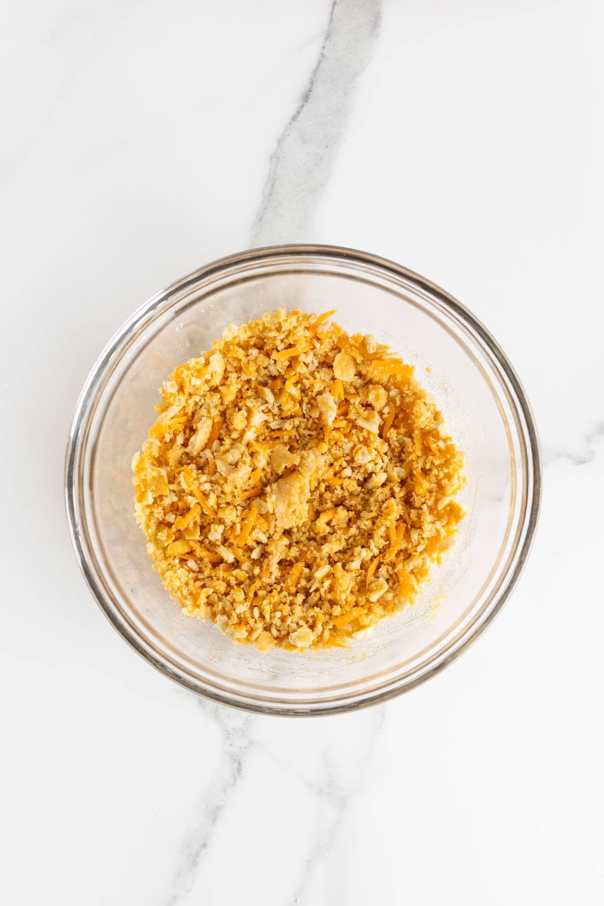 A separate bowl with crushed crackers, shredded cheese, and melted butter mixed for the topping