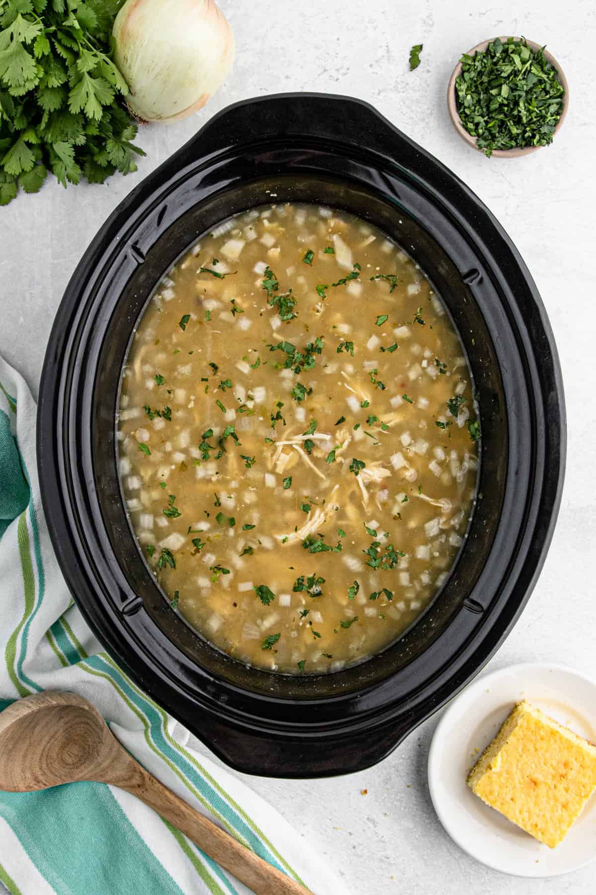 Slow cooker full of white chicken chili topped with chopped fresh cilantro